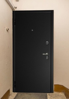 Входная дверь черного цвета в брежневке, вид снаружи с темной отделкой