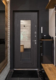 Входная дверь черного цвета в интерьере в стиле лофт, вид внутри со светлой отделкой