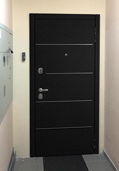 Входная дверь черного цвета в интерьере в стиле минимализм, вид снаружи с темной отделкой