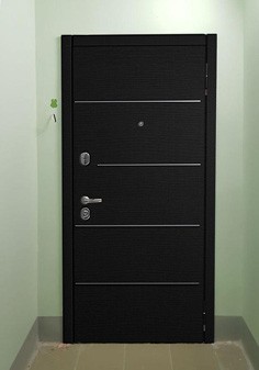 Входная дверь черного цвета в квартире-студии, вид снаружи с темной отделкой