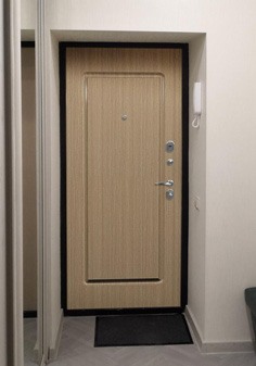 Входная дверь черного цвета в новостройке, вид внутри со светлой отделкой