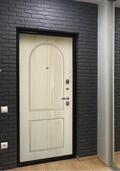 Входная дверь черного цвета в темном интерьере, вид внутри со светлой отделкой